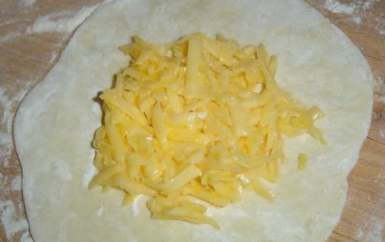 На середину «коржика» выложите начинку из сыра, соберите кончики кусочка теста и соедините их сверху