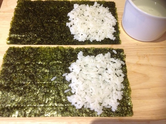 Примерно 1/3 часть нори заполняем слоем риса